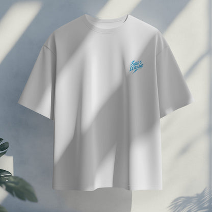 White t-shirt with a small blue logo on a light gray background